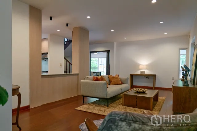 Detached House for rent in Watthana, Bangkok - Open-plan lounge with wood flooring, built-in counter and large windows.