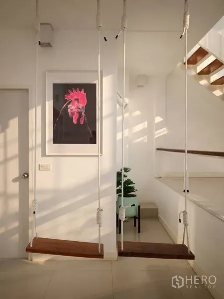 Townhouse for rent in Khlong Toei, Bangkok - Bright hallway with two indoor swings, staircase and wall art in a modern Bangkok townhouse.