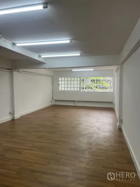 Shophouse for rent in Watthana, Bangkok - Bright upper-floor room with white walls, wood-look flooring and fluorescent strip lights