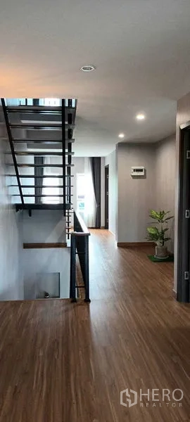 Townhouse for rent or sale in Saphan Sung, Bangkok - Upper hallway with floating stairs, wood floors and abundant natural light.