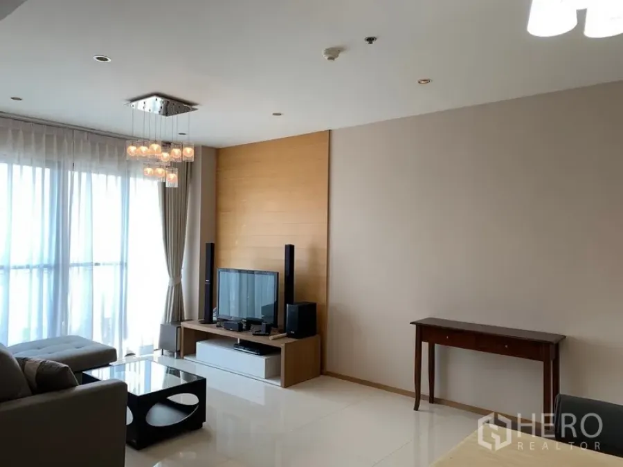 Condominium for rent in Khlong Toei, Bangkok - Bright living room with floor-to-ceiling windows, chandelier, sofa and media console.