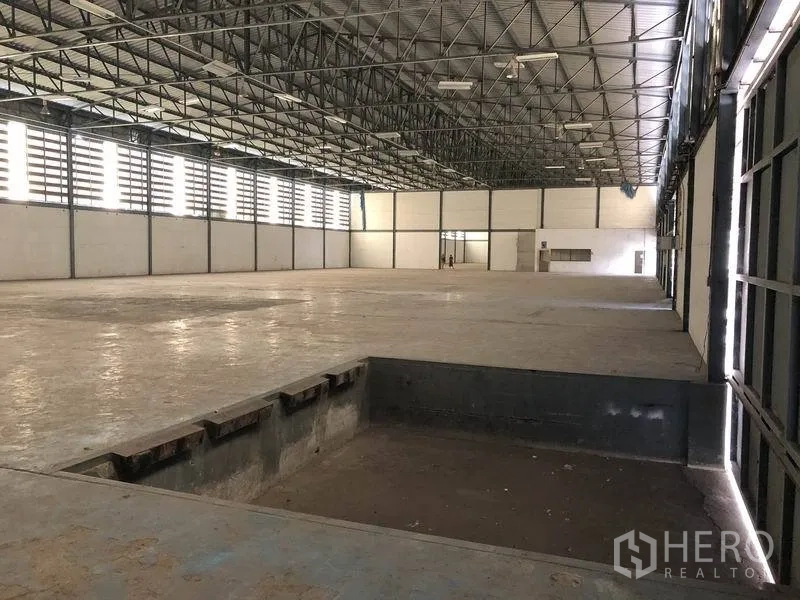 Warehouse for rent in Khlong Luang, Pathum Thani - Warehouse interior showing a recessed loading pit, wide column-free floor and metal-framed windows.