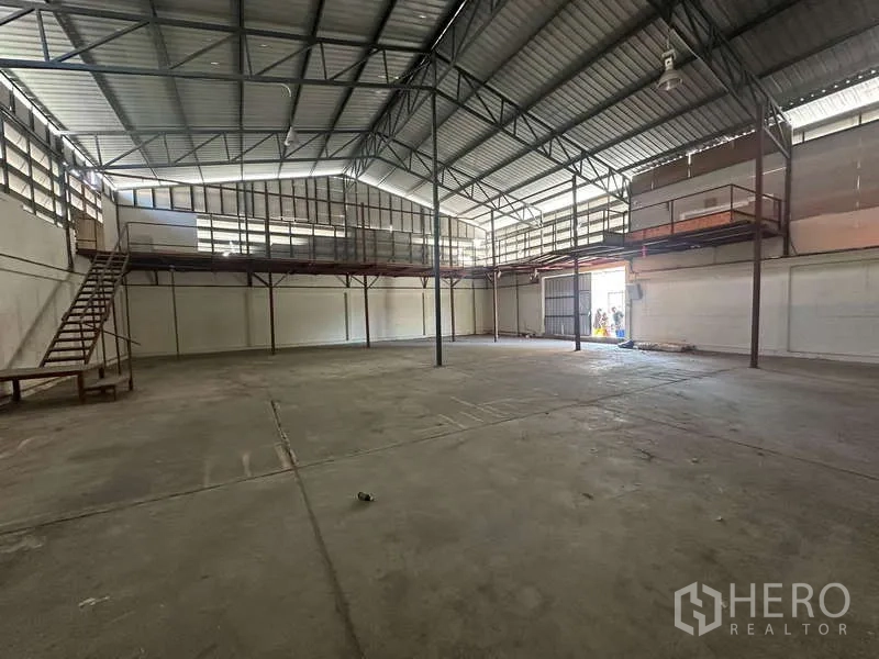 货栈 出租在Suan Luang, Bangkok - 挑高仓库内部，钢结构屋顶与夹层平台，可见大型装卸门。