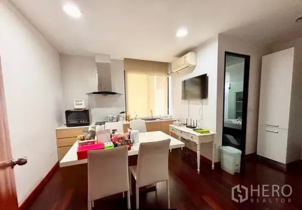 Home Office for rent in Watthana, Bangkok - Pantry kitchen and dining area with cooktop, white table and wall-mounted TV.