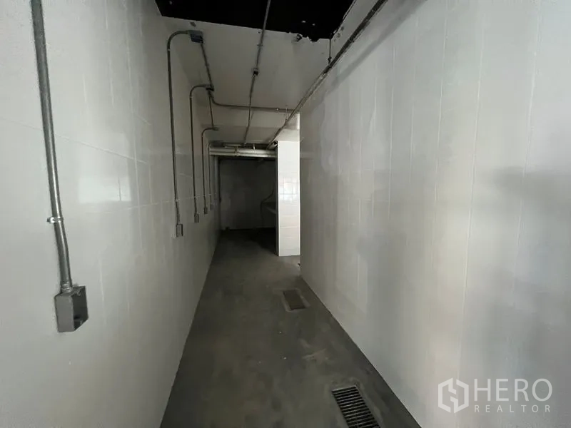 Retail Space for rent in Watthana, Bangkok - Long tiled corridor with floor drains and exposed conduits for ventilation and power.