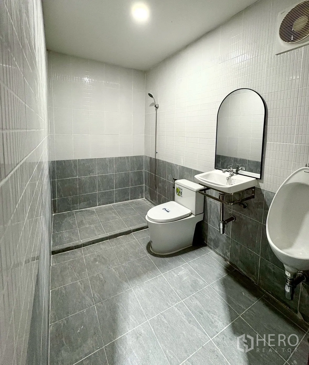 Warehouse for rent in Suan Luang, Bangkok - Clean tiled restroom with toilet, urinal, sink and shower inside the warehouse.