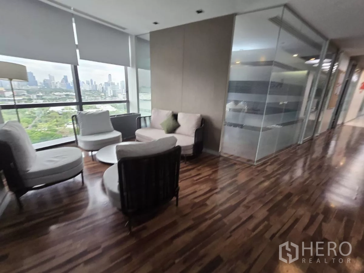 Office Space for rent in Watthana, Bangkok - Seating area by floor-to-ceiling windows and glass-partitioned rooms.