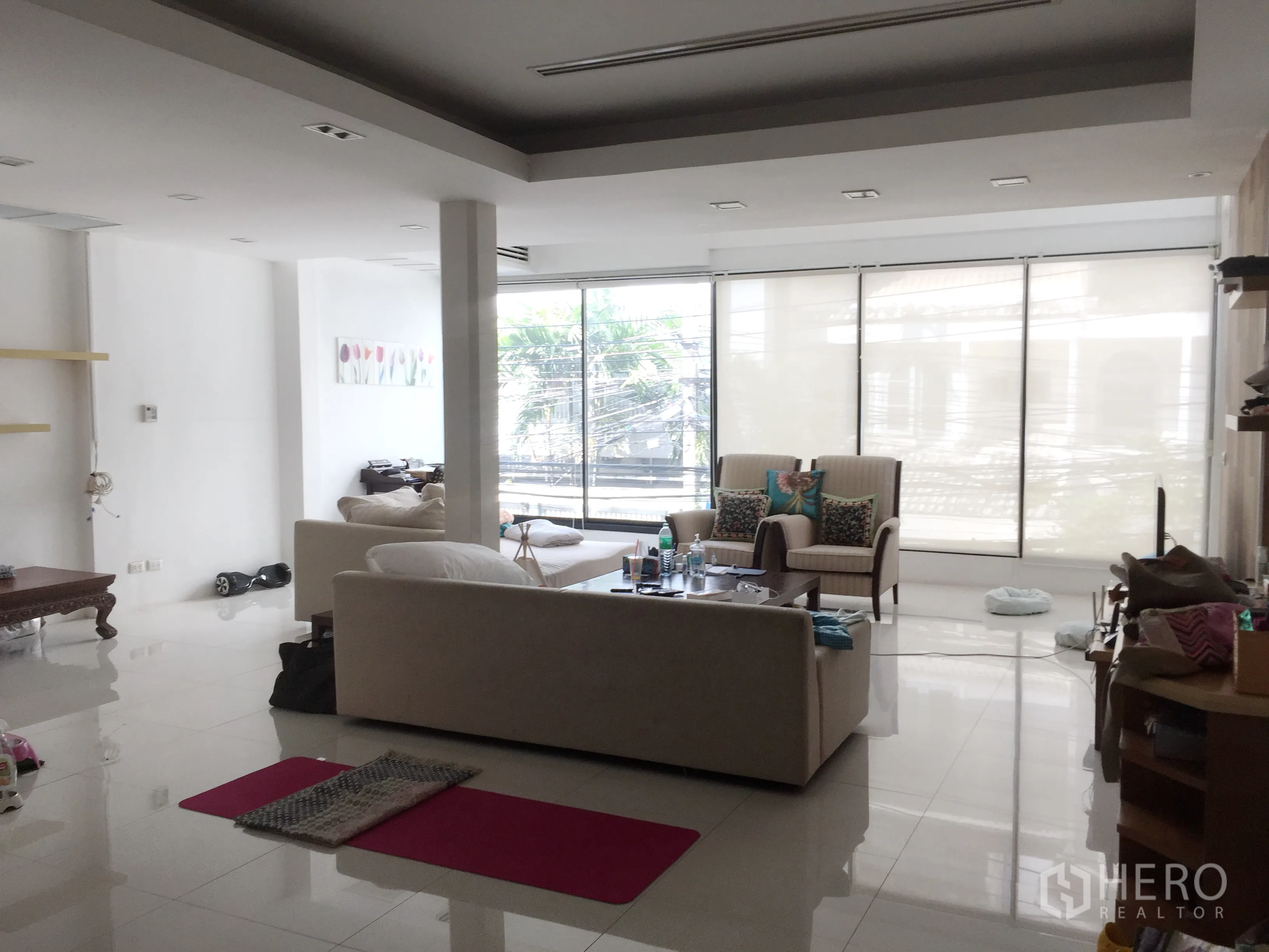 Townhouse for rent in Khlong Toei, Bangkok - Wide living area with lounge seating, large sliding windows and bright white tiled floors.
