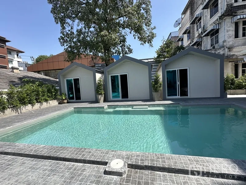 Home Office for rent in Suan Luang, Bangkok - Clear turquoise pool in front of three modern cabins on gray deck.