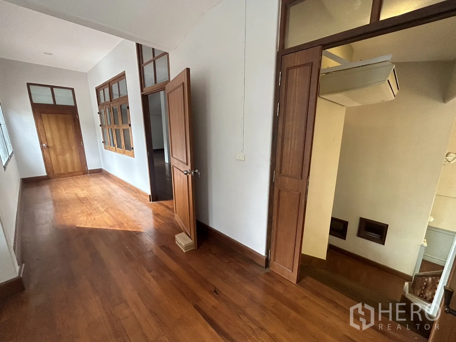 Retail Space for rent in Bangkok - Upper-floor corridor with wooden doors, windows and built-in air conditioning unit.
