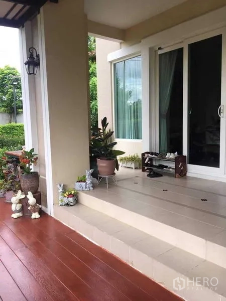 Detached House for sale in Bang Kruai, Nonthaburi - Covered front porch with steps, potted plants and a sliding glass door.