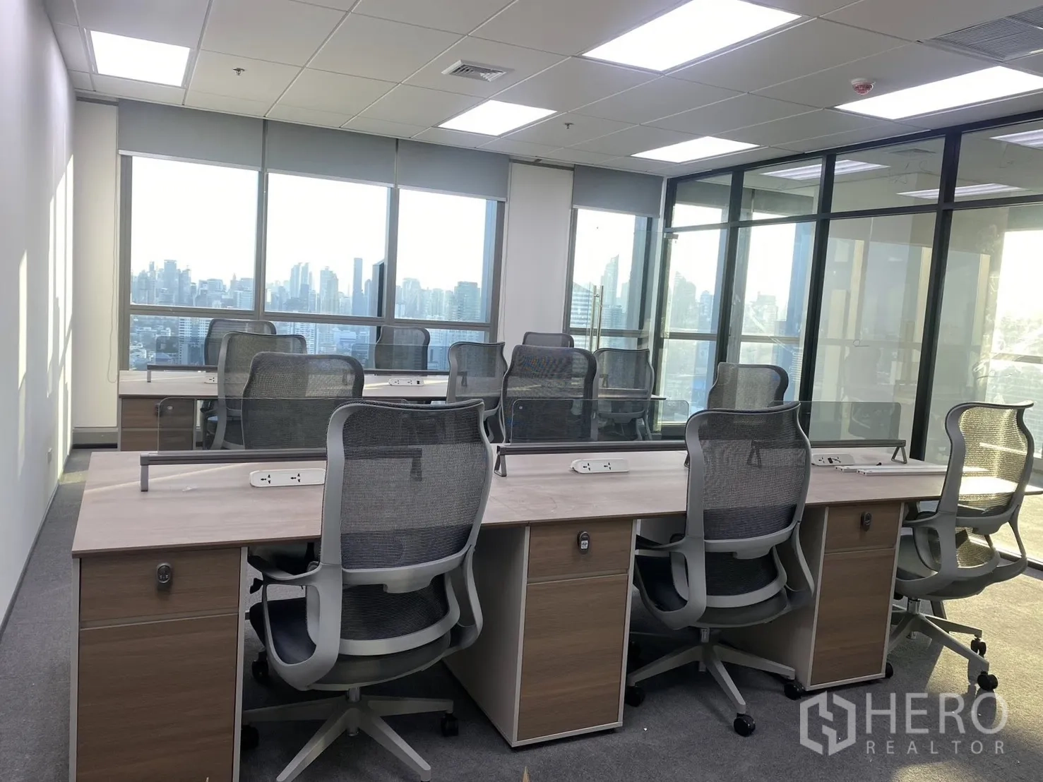 办公空间 for rent in Huai Khwang, Bangkok - 长排工位配网面椅与电源轨，超大窗户眺望天际线。