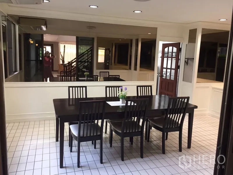 Townhouse for rent in Watthana, Bangkok - Formal dining room with dark wood table, six chairs and surrounding windows.