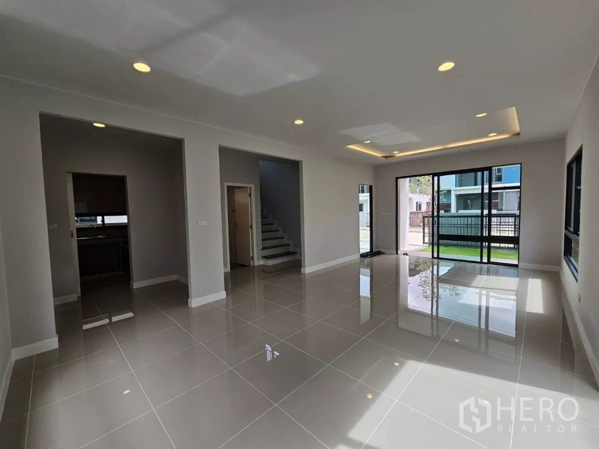 Detached House for sale in Lam Luk Ka, Pathum Thani - Bright open-plan living area with large sliding glass doors and glossy tiled floors.