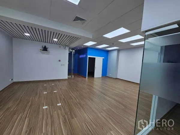 办公空间 出租在Sathon, Bangkok - 开放式办公室，木纹地板、LED灯面板、蓝色点缀墙与玻璃入口