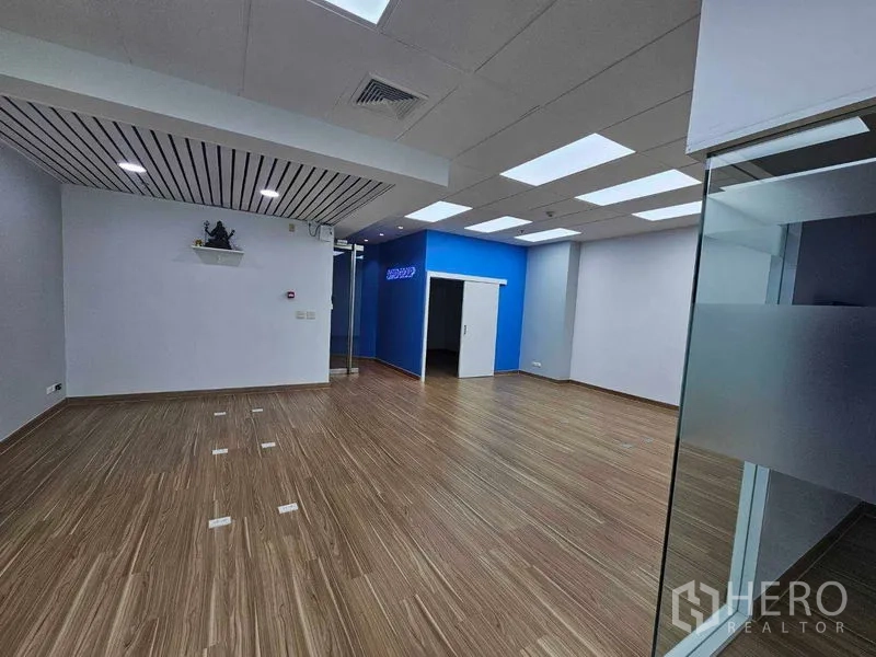 办公空间 出租在Sathon, Bangkok - 开放式办公室，木纹地板、LED灯面板、蓝色点缀墙与玻璃入口