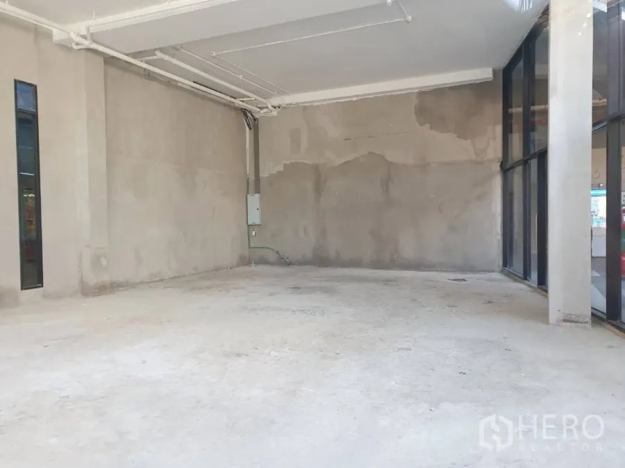 Retail Space for rent in Watthana, Bangkok - Unfitted retail unit with high ceiling, raw concrete floor and floor‑to‑ceiling glass frontage.
