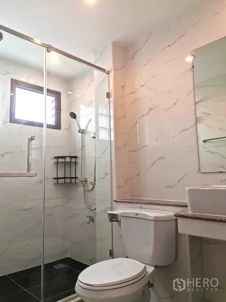 Detached House for rent in Bang Rak, Bangkok - Bathroom with glass-enclosed shower, toilet, and marble-effect tiles providing a clean modern look.