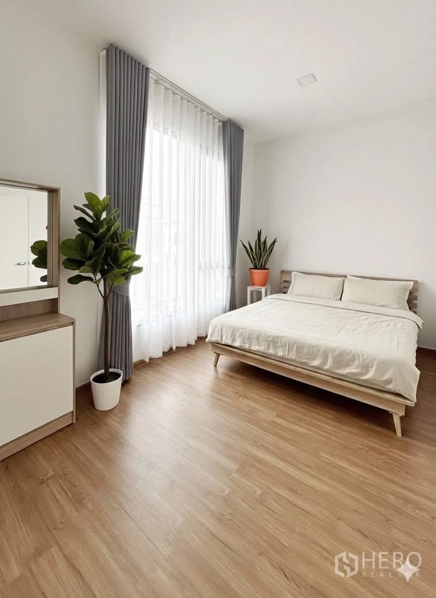 Townhouse for rent in Bang Phli, Samut Prakan - Sunlit bedroom with double bed, wood flooring, sheer drapes and potted plants.