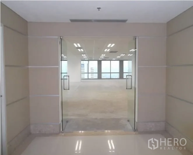 Office Space for rent - Glass double doors from the corridor opening into a bright office floor with city views ahead.