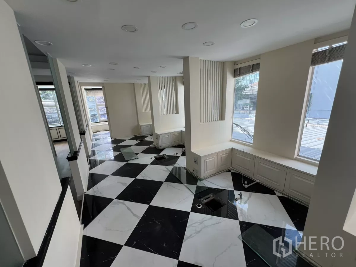 Retail Space for rent - Bright retail interior with large windows and a black‑and‑white checkerboard marble floor.