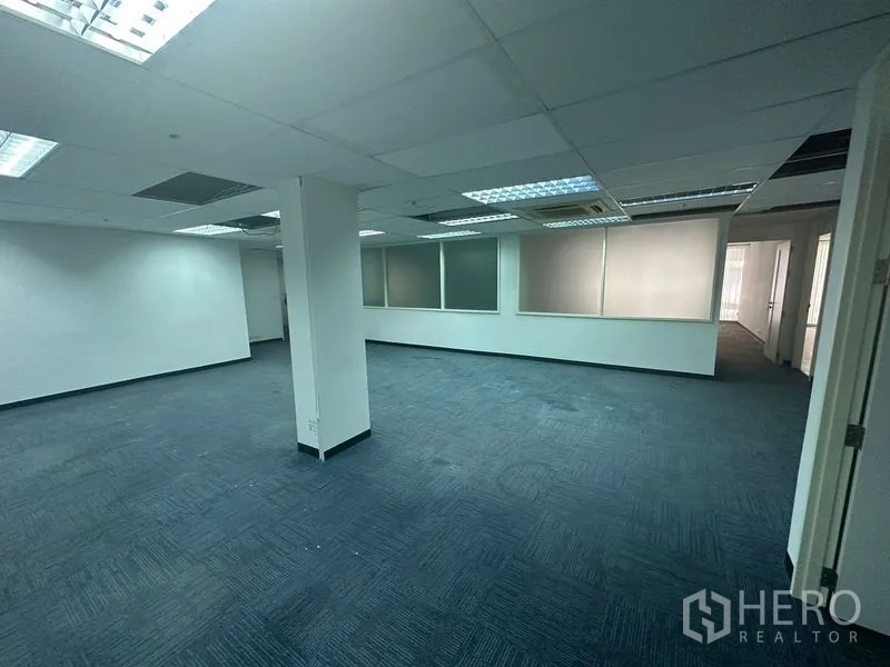 Office Space for rent in Khlong Toei, Bangkok - Spacious open office zone with blue carpet, ceiling lights and frosted interior windows.