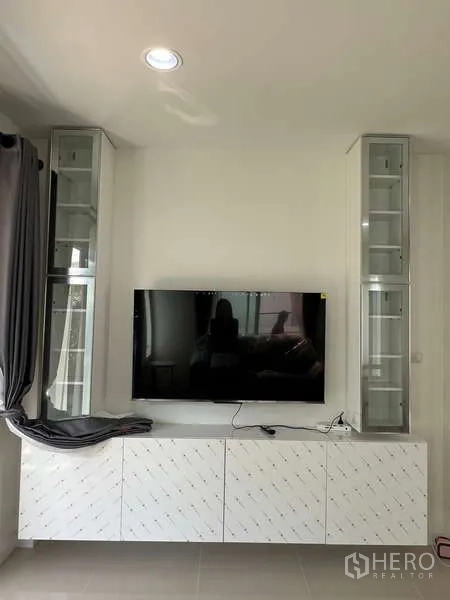 Detached House for rent in Bang Kapi, Bangkok - Living room media wall with mounted TV and white storage cabinet.