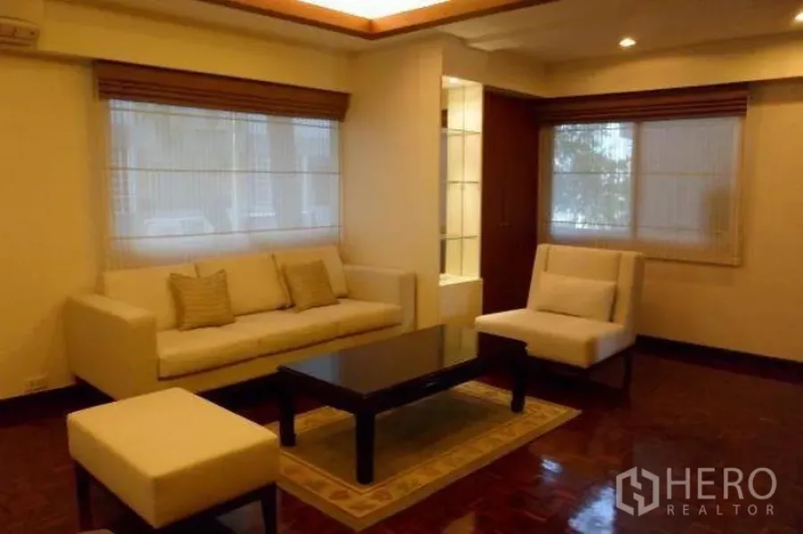 Condominium for rent in Pathum Wan, Bangkok - Warm living room with cream sofas, coffee table, recessed ceiling lights and parquet floors.
