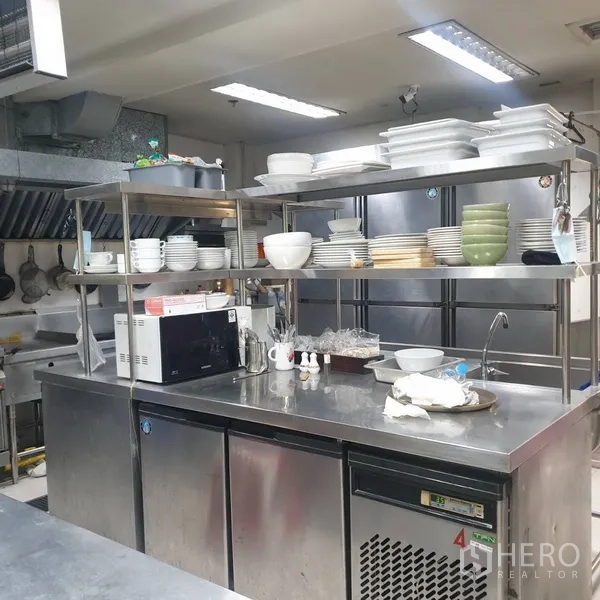 Retail Space for rent in Khlong Toei, Bangkok - Back-of-house prep station with stainless counters, open shelving of dishware, and refrigeration units.