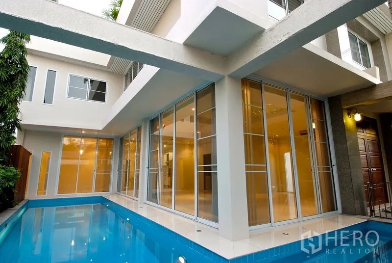 Detached House for rent in Watthana, Bangkok - Exterior view of the house with full‑height glass beside a private lap pool.