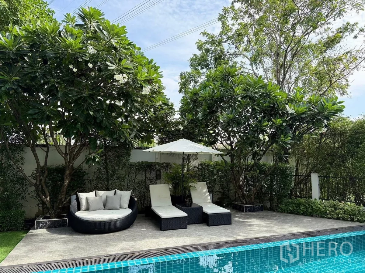 Detached House for rent or sale in Prawet, Bangkok - Sun deck by the saltwater pool with loungers shaded by frangipani trees.