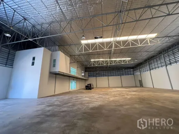 Warehouse for rent in Prawet, Bangkok - Spacious high-ceiling warehouse interior with insulated roof and mezzanine office block.