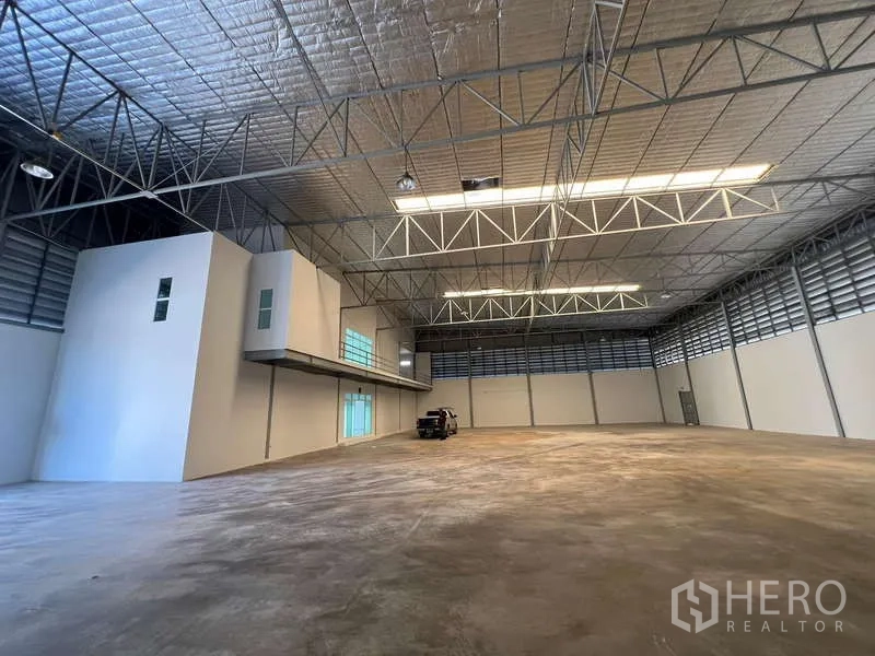 Warehouse for rent in Prawet, Bangkok - Spacious high-ceiling warehouse interior with insulated roof and mezzanine office block.