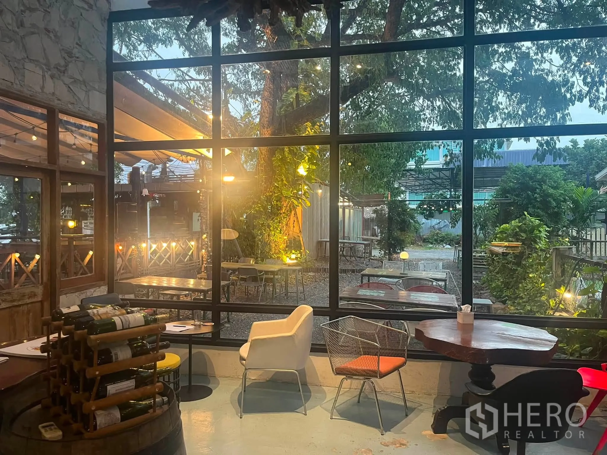 Retail Space for rent in Watthana, Bangkok - Retail interior with floor-to-ceiling windows facing a leafy garden patio and eclectic seating.