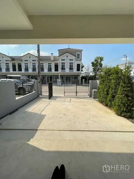 Detached House for rent in Prawet, Bangkok - Covered carport and gated driveway facing the community street.