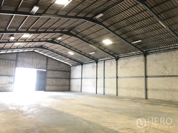 Warehouse for rent in Khlong Luang, Pathum Thani - Bright warehouse interior with high gable roof, ventilation block walls and a large entrance letting in light.