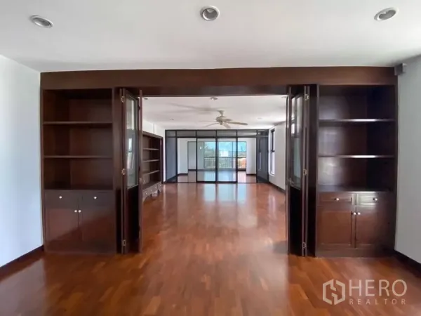 Home Office for rent in Phra Khanong, Bangkok - Spacious room with dark wood built-in shelving, glass partition, ceiling fan and polished timber floors.