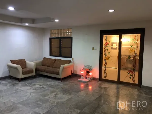 带办公室的家 出租在Phra Khanong, Bangkok - 宽敞客厅，沙发、嵌灯、石质地面与花卉彩绘玻璃推拉门。