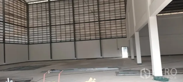 Warehouse for rent in Phra Pradaeng, Samut Prakan - Interior corner with tall louvered ventilation panels and a side access door.