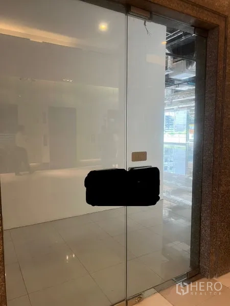 Retail Space for rent - Frameless glass door entry to the retail unit with handle and lit interior.