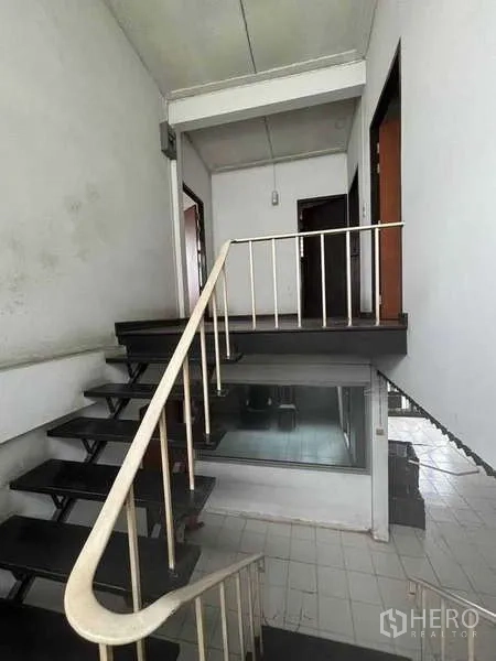 独立式住宅 出租在Suan Luang, Bangkok - 楼梯平台带金属扶手，通往房间的门与室内观景窗相连。
