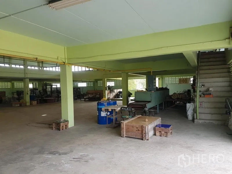 工厂 出租或出售在Nong Chok, Bangkok - 一层开放式车间，混凝土地面、结构立柱、管线到位，并有楼梯通往上层。