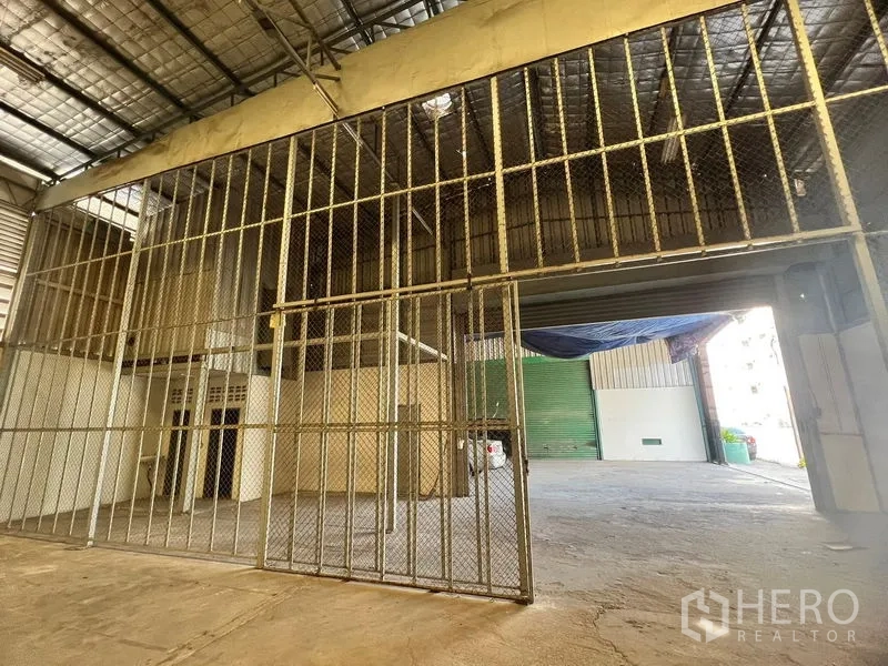 Warehouse for rent in Suan Luang, Bangkok - Secure caged storage zone beneath a high roof next to the loading area.