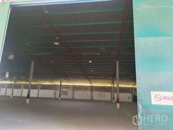 Warehouse for rent in Mueang Rayong, Rayong - Wide interior of the warehouse with a high steel roof, columns and concrete floor viewed through an open sliding door.