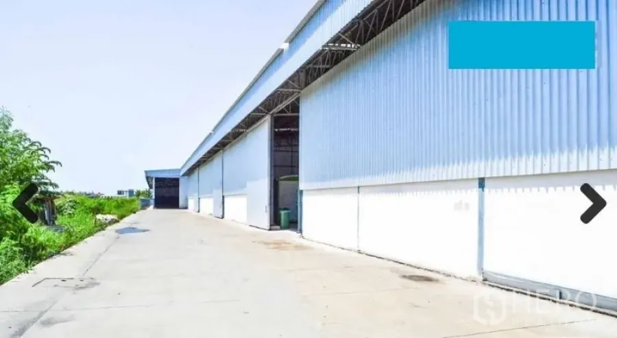 Warehouse for rent in Bang Phli, Samut Prakan - Exterior of warehouse with multiple large bays and a truck-friendly apron under a metal roof overhang.