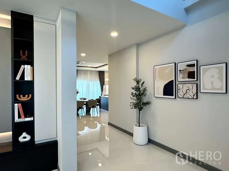 Detached House for rent in Bang Phli, Samut Prakan - Hallway leading to dining room with wall art and decorative shelving.