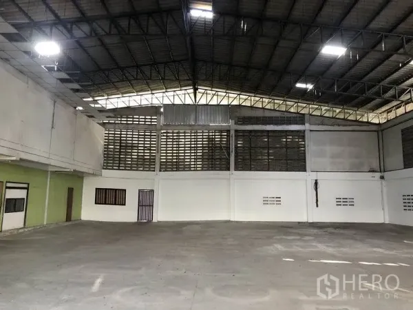 Warehouse for rent in Khlong Sam Wa, Bangkok - Open-span warehouse interior showing high steel truss roof and ventilated block walls.