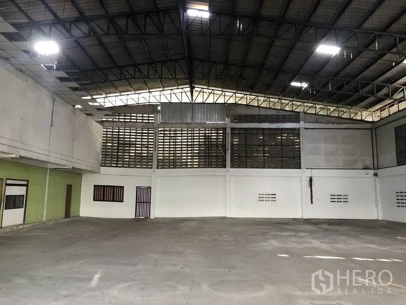 Warehouse for rent in Khlong Sam Wa, Bangkok - Open-span warehouse interior showing high steel truss roof and ventilated block walls.