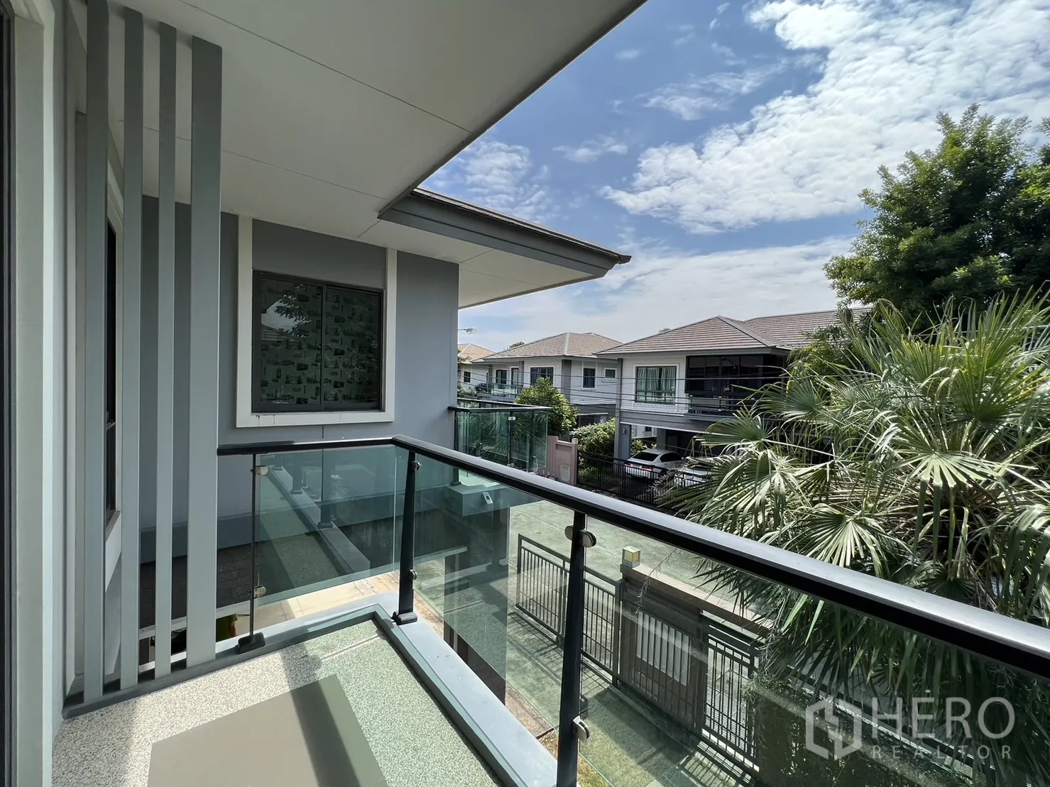 独立式住宅 出售在Suan Luang, Bangkok - 玻璃栏杆阳台，俯瞰宁静绿树成荫的街区。