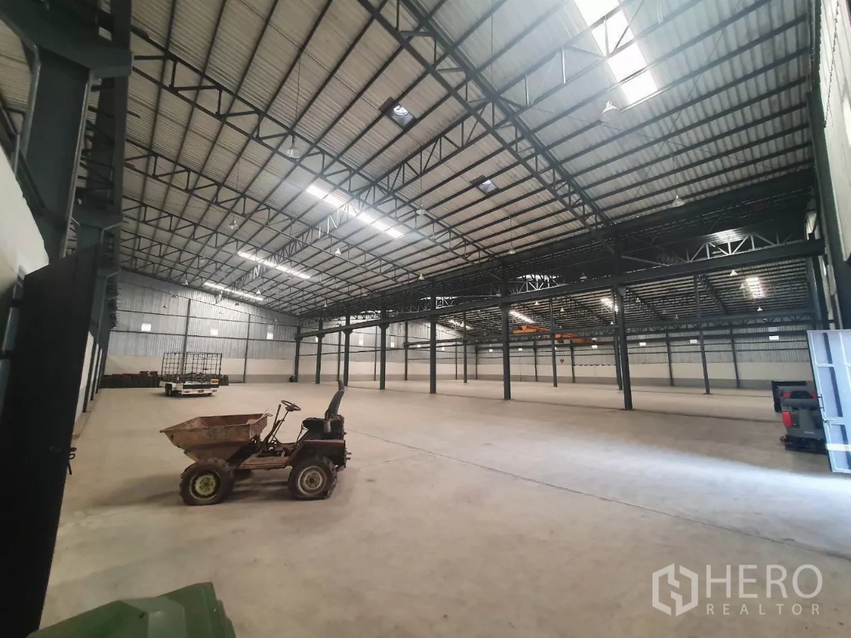 Factory for rent in Mueang Samut Prakan, Samut Prakan - Expansive production hall with concrete floor and ventilation panels.